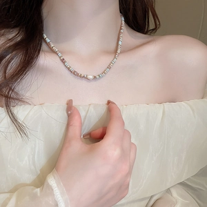 Gros plan d'un collier de perles bleues et blanches porté par un mannequin femme