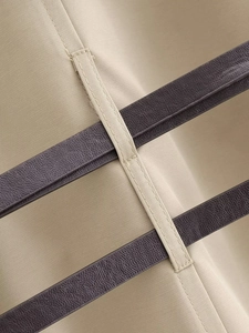 Dettaglio del tessuto kaki e pelle marrone su un trench ampio con cintura coordinata