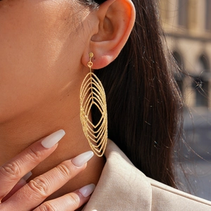 Close-up of golden multi-layer hollow leaf earrings with textured metallic finish