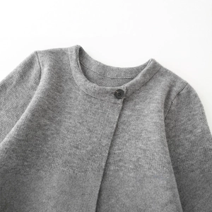 Cappotto minimalista in maglia grigia con scollo rotondo e dettaglio a bottone singolo