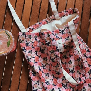 Detailed view of floral canvas tote bag with pink roses on wood surface with drink