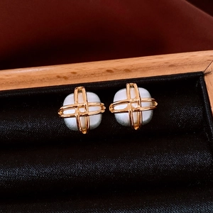Detailed close-up of gold-plated square cross earrings featuring central white pearls