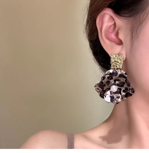 Detail of leopard print flower earrings with gold petals and a central pearl accent