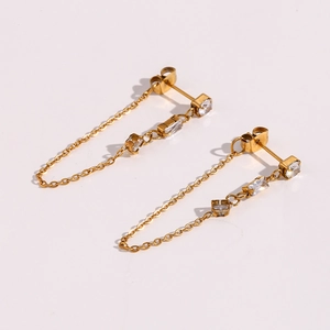 Detail view of gold chain tassel earrings featuring white square zircon stones