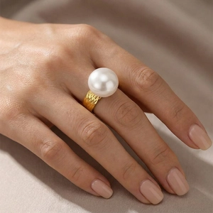 Detail view of a gold hammered metal ring featuring a large elegant white pearl on model