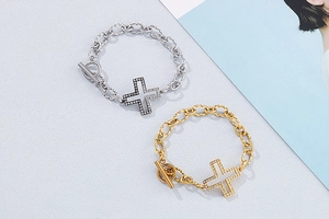 Detail of gold and silver cross charm bracelets with OT toggle clasp and crystal inlay