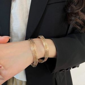 Detailed view of layered gold thin bangles on wrist with elegant polished metal finish