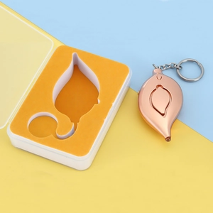 Detail view of leaf-shaped rose gold personal alarm keychain with retail gift packaging