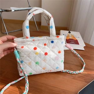 Detailed close-up of quilted floral crossbody bag with colorful woven strap on wood