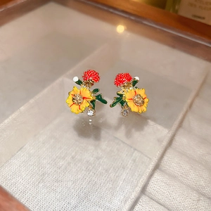 Macro view of sweet floral stud earrings with yellow petals and red berry enamel details