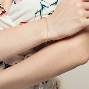 Close-up of a gold S925 sterling silver chain bracelet with sparkling flower pendant