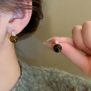 Vue détaillée d'une boucle d'oreille perle avec base dorée et zircon sur l'oreille
