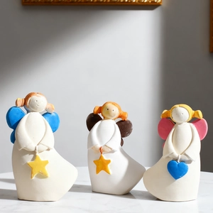 Trois figurines d'anges en résine avec ailes colorées tenant des cœurs sur marbre blanc