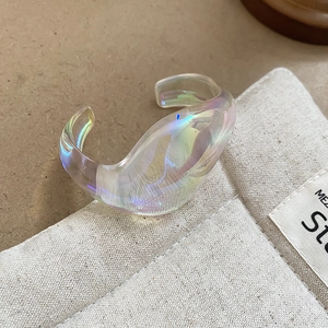 Close-up of iridescent acrylic bangle with chunky wave design and laser rainbow finish