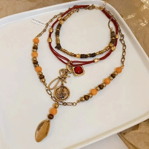 Detail of bohemian layered necklace with wood beads, red gem, and gold coin pendant