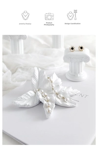 Macro detail of white leaf tray and Greek column earring stand for jewelry photography