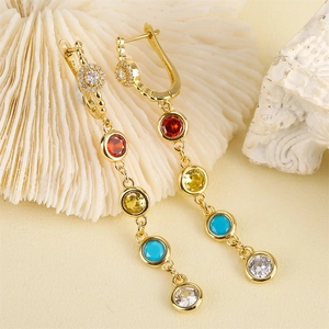 Gold bohemian tassel earrings with vibrant colorful zircon stones on artistic white coral base