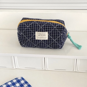 Close-up of quilted navy plaid pouch with yellow zipper and mint green puller detail