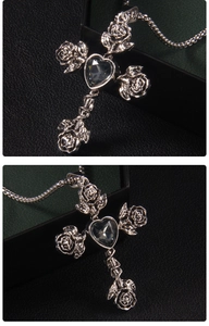 Detail view of silver cross pendant with 3D roses and a dark heart gemstone centerpiece