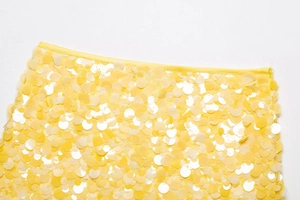 Gros plan détaillé sur les paillettes jaunes brillantes et la taille de la mini-jupe