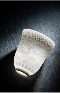Macro detail of white mutton fat jade ceramic tea cup with relief phoenix carving