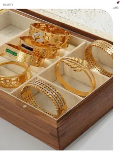 Detailed macro view of hollow leaf patterns and gemstone bangles in a wood jewelry box