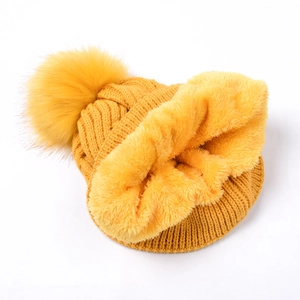 Detail view of yellow knit beanie with thick fleece lining and faux fur pompom decoration