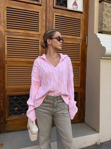 Detail of pink cable knit sweater featuring a wide lapel collar and soft V-neckline