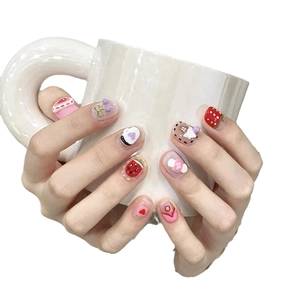 Pink dopamine donut press-on nails with strawberry and 3D heart designs on a white mug