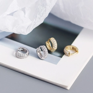 Macro shot of silver and gold wide hoop earrings with multi-row pavé white zircon stones