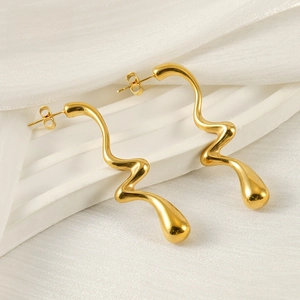 Detalle macro de pendientes de lava chapados en oro de 18K con textura de metal fluido
