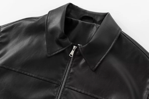 Detail view of black faux leather aviator jacket featuring silver metal zipper and lapel