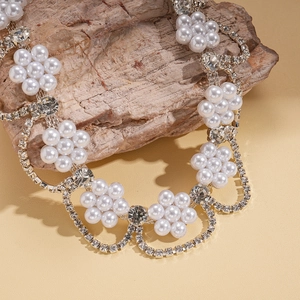 Détail du collier fleurs en perles de luxe avec strass brillants sur pierre texturée