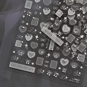 Macro shot of 3D embossed white lace nail stickers with hearts and pearls