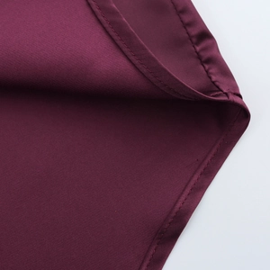 Macro shot of dark red satin shirt fabric showing fine texture and premium edge stitching