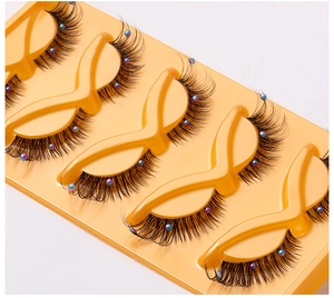 Close-up of false eyelashes with colorful pearl decorations on a yellow tray