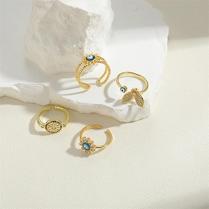 Gold evil eye rings set featuring sunflower, butterfly, and compass designs on white rock