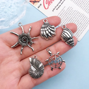 Detailed close-up of antique silver sea creature charms held in palm for DIY jewelry