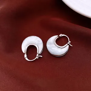 U-shaped mother of pearl earrings in rose gold finish on elegant red silk background