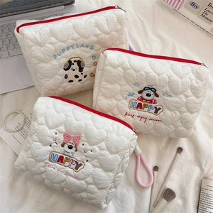 Detailed view of white heart-quilted cosmetic bags with cute puppy embroidery and red zipper