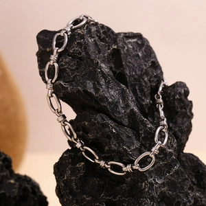 Detailed macro of silver industrial chain links with textured screw clasps on dark rock