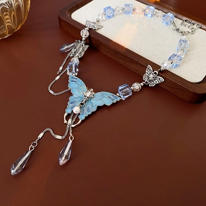 Vue détaillée d'un collier papillon avec pendentif bleu, perles et cristaux scintillants
