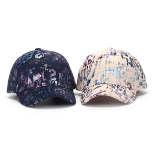 Detail view of two printed baseball caps in navy and beige with abstract artistic patterns