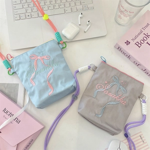 Flatlay von Canvas-Umhängetaschen mit Schleifenbestickung und gewebtem Gurt