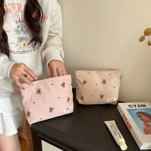 Close-up of cute bear embroidery on corduroy cosmetic bags in pink and beige colors