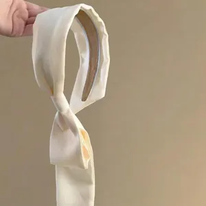 Close-up of elegant cream silk headband featuring long flowing ribbons in French style