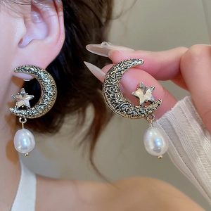 Detail view of vintage gold moon and star earrings with drop pearls and sparkling crystals