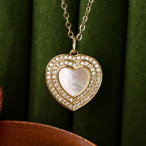Golden heart necklace with mother of pearl and zircon halos on green velvet