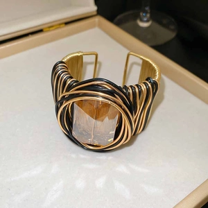 Détail d'un bracelet manchette tressé torsadé avec un grand cristal rectangulaire ambre