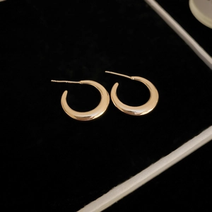 Close-up of golden C-shaped metal hoop earrings placed in a black velvet jewelry box